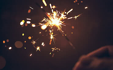 Person celebrating at night by holding sparkler.