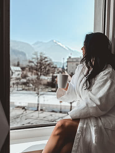 Frau genießt Ausblick auf die Winterlandschaft im Hotel Victoria Meiringen