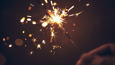 Person celebrating at night by holding sparkler.