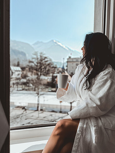 Frau genießt Ausblick auf die Winterlandschaft im Hotel Victoria Meiringen