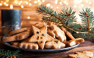 1180203969 Leckere hausgemachte Weihnachtsplätzchen mit festlichen goldenen Lichtern