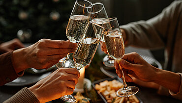 1346201607 vier Personen beim Weihnachtsessen mit Champagner an einem eleganten Esstisch mit Kerzen sitzen